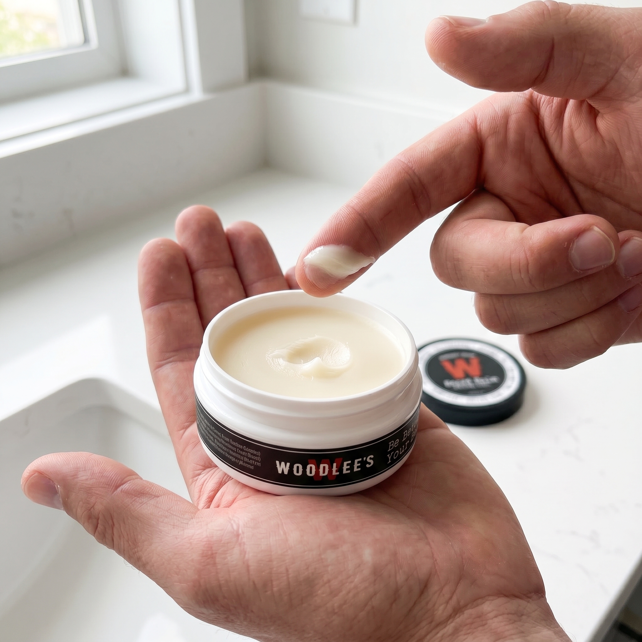 Fingertip scoop of Woodlee's Beard Balm from an open 2 oz tin